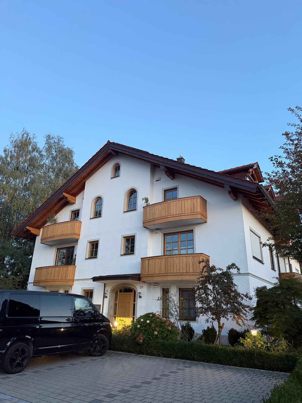 Mehrfamilienhaus mit Holzbalkonen und hell verputzter Fassade