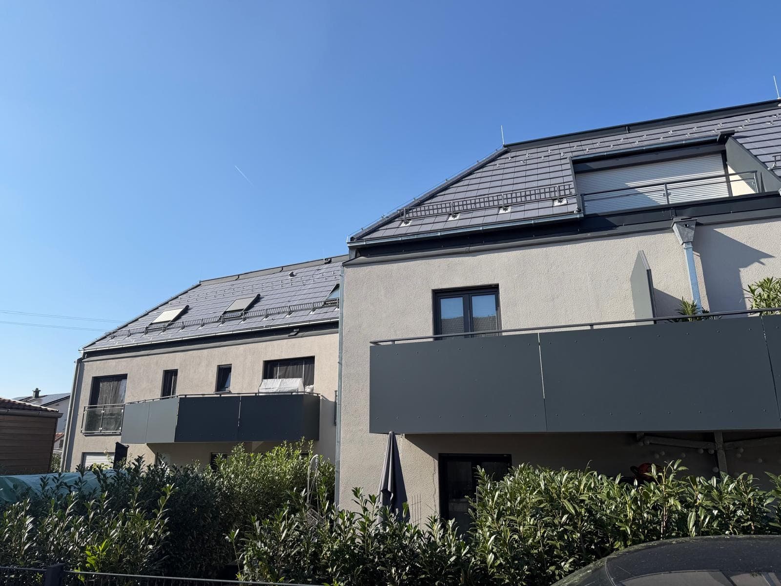 Moderne Wohnanlage mit großen, glatt verputzten Wandflächen und dunklen Balkonen