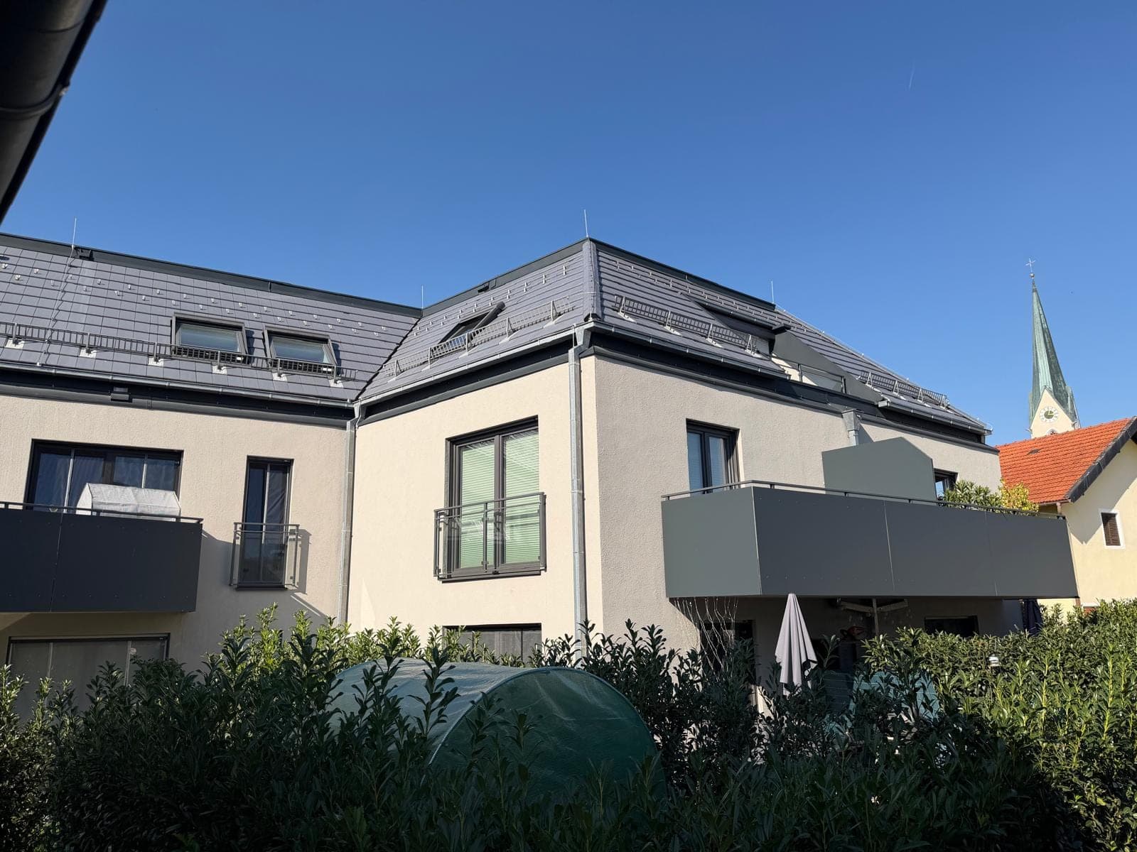 Wohnanlage mit hell verputzter Fassade und dunklen Balkonbrüstungen